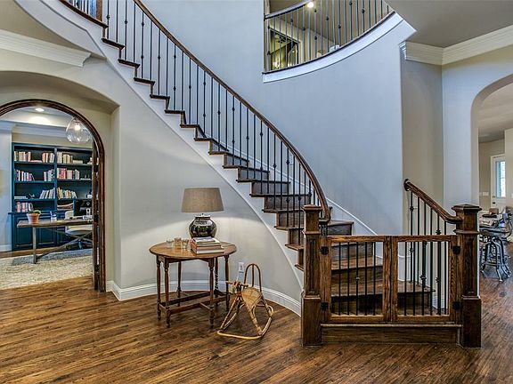 Entrance Into Stunning Foyer; Curved Iron Stairway with Wooden Steps and Hand Scraped Wood in Living Areas; Study with French Doors on the Left