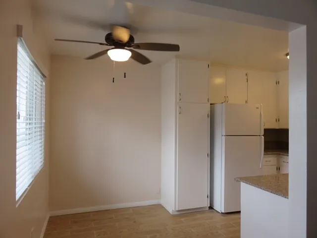 Dining area with fan, next to kitchen area. Tile floor.