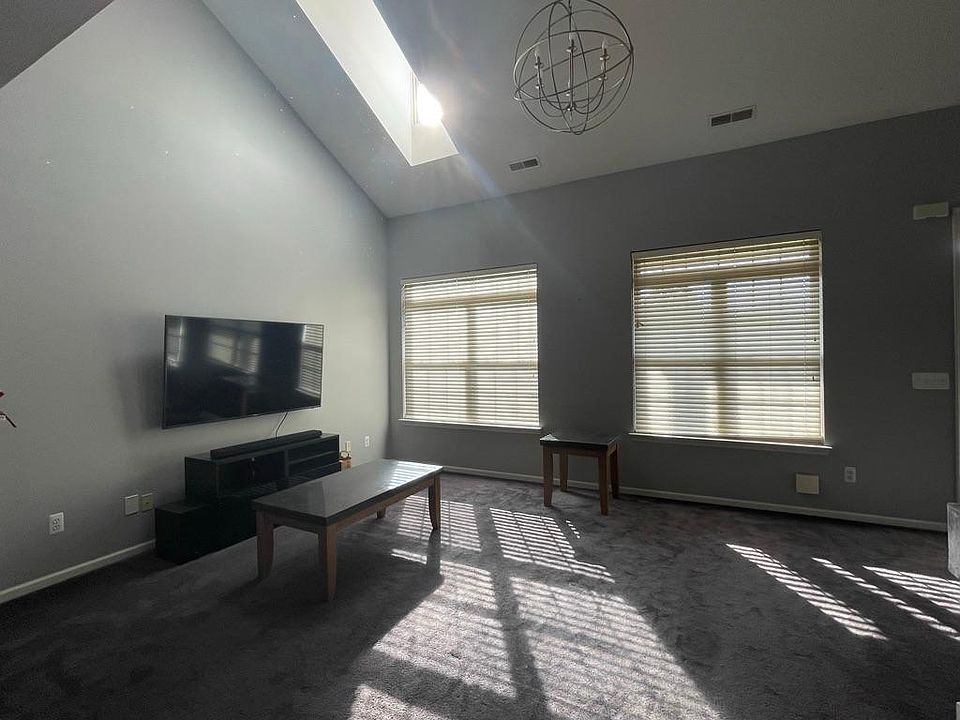 living room with skylight and balcony access. 65 in tv for scale