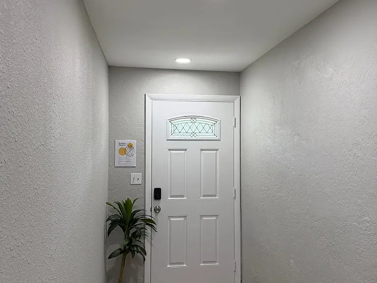 Welcoming entry hallway with durable wood-look flooring, recessed lighting, and a front door with decorative glass inset.
