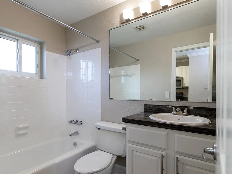 Enjoy selfcare in a space that echoes the kitchen's charm with black fusion counter tops and white shaker cabinetry.