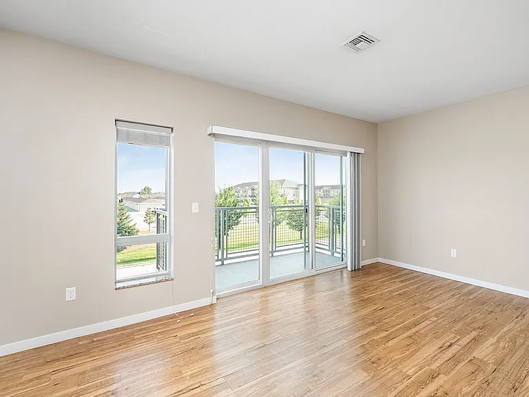 Bright, spacious living room with large windows and hardwood floors opening onto a private balcony with scenic views. Bright, spacious living room with large windows and hardwood floors opening onto a private balcony with scenic views.