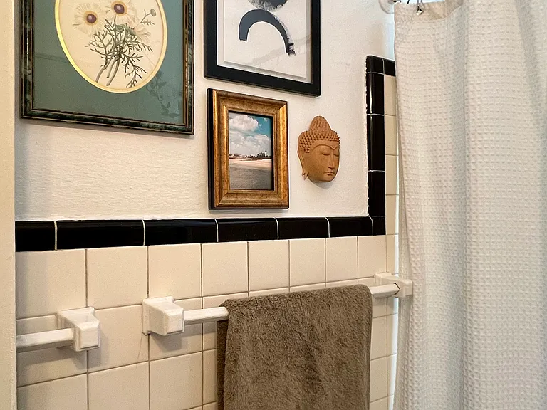 Black and white tiled bath with tub/shower combo and window