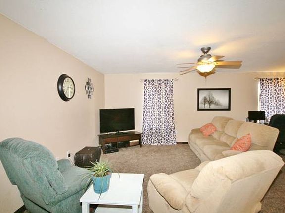 The living room is to the left as you enter.  Plenty of room for large furniture in this home plus it offers a ceiling fan overhead. Newer carpet and stylish curtains round out the living area.