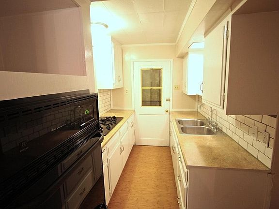looking into Galley Kitchen from dining area includes newer built in double oven, deep pull out drawers under gas range, and pass thru to living room, .and door out to covered patio.