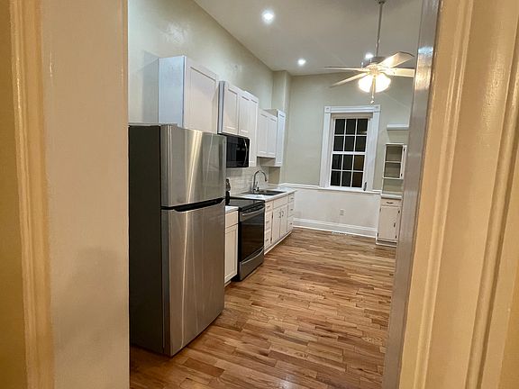 This side has new cabinets but the sink base is the original wood one, has white subway tiles on the walls under the cabinets, and new stainless steel appliances.
