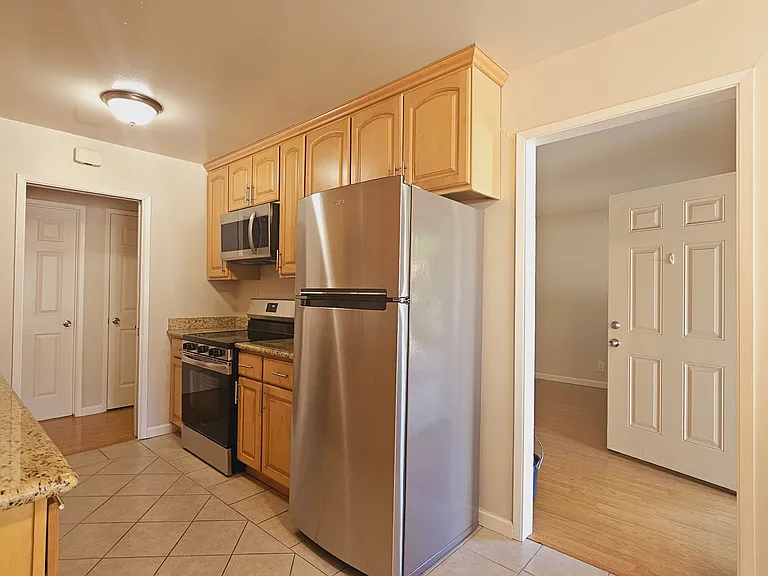 Maple kitchen cabinets with granite countertop. New stainless steel refrigerator.