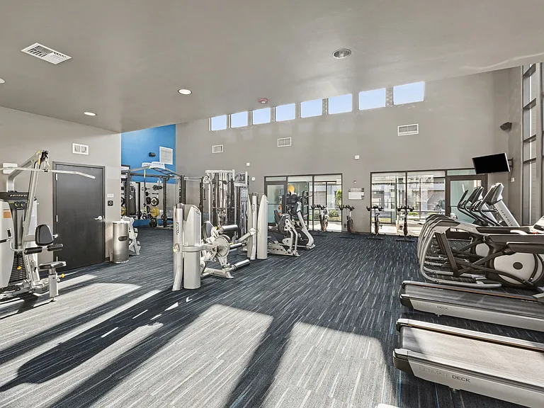 Aspire Apartments Tracy CA amenities gym with treadmills, weights, and other exercise equipment.
