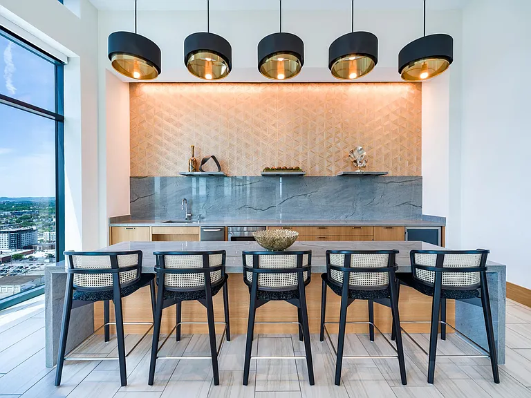 Community bar with tailored seating, layered lighting, and stone surfaces designed for casual gathering, conversation, and hosted events.