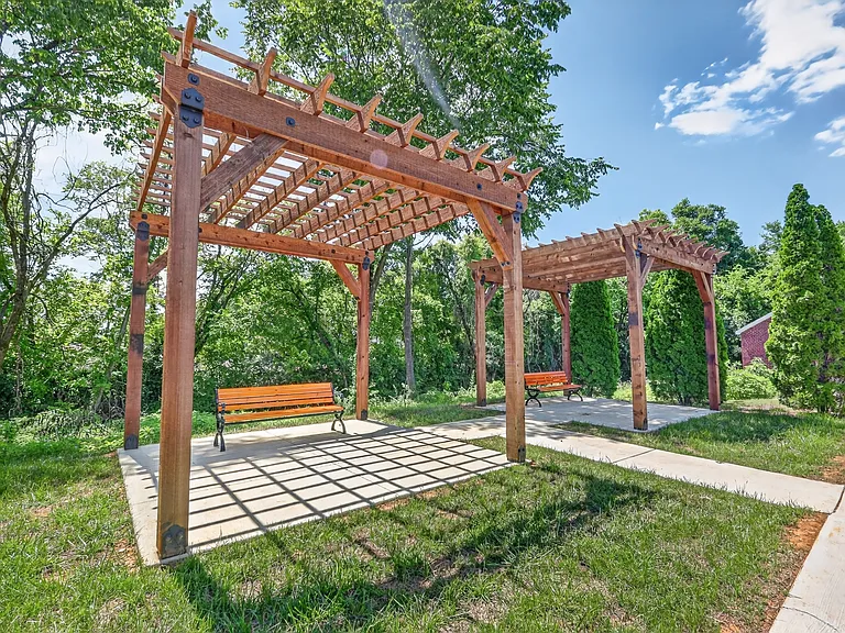 Shaded pergola and bench seating area designed for relaxation and community enjoyment.