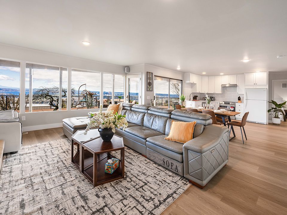 A bright and inviting space with a plushleather sectional, and a stylish coffee table with games. Large windows let in natural light and offer a serene view of the greenery outside.