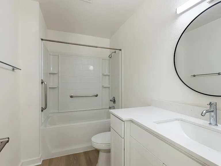 Modern bathroom with sleek white fixtures, a spacious bathtub, and elegant round mirror. Modern bathroom with sleek white fixtures, a spacious bathtub, and elegant round mirror.