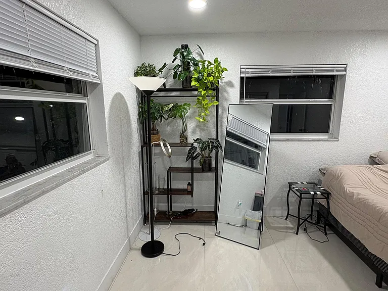 Bedroom with tile flooring, two windows, and space for a bed plus a small desk or shelving for storage.