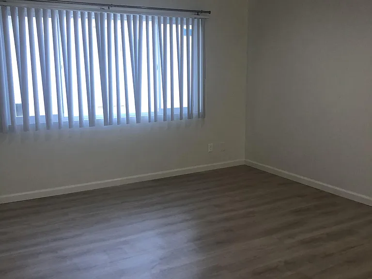Beautiful bedroom recent lighting blinds hardwood flooring.