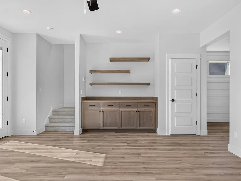 Main living area with built in cabinets and shelving. Storage room under stairs