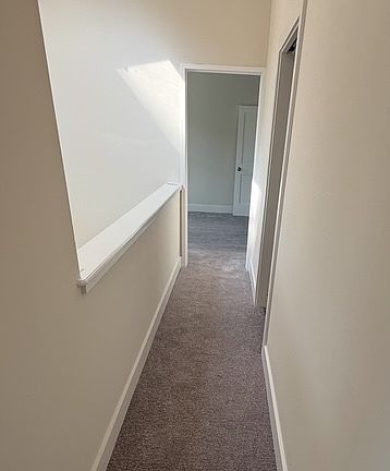 Second floor hallway with cathedral ceilings with brand new carpeting and natural light