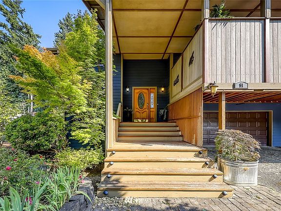 As you approach.  Garage to the right is two car, with shop space.  Fenced area, above and to the right is the covered deck area.