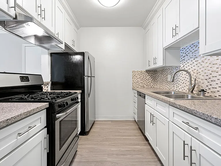 Custom tiled kitchen with stainless steel fridge, sink, and oven.