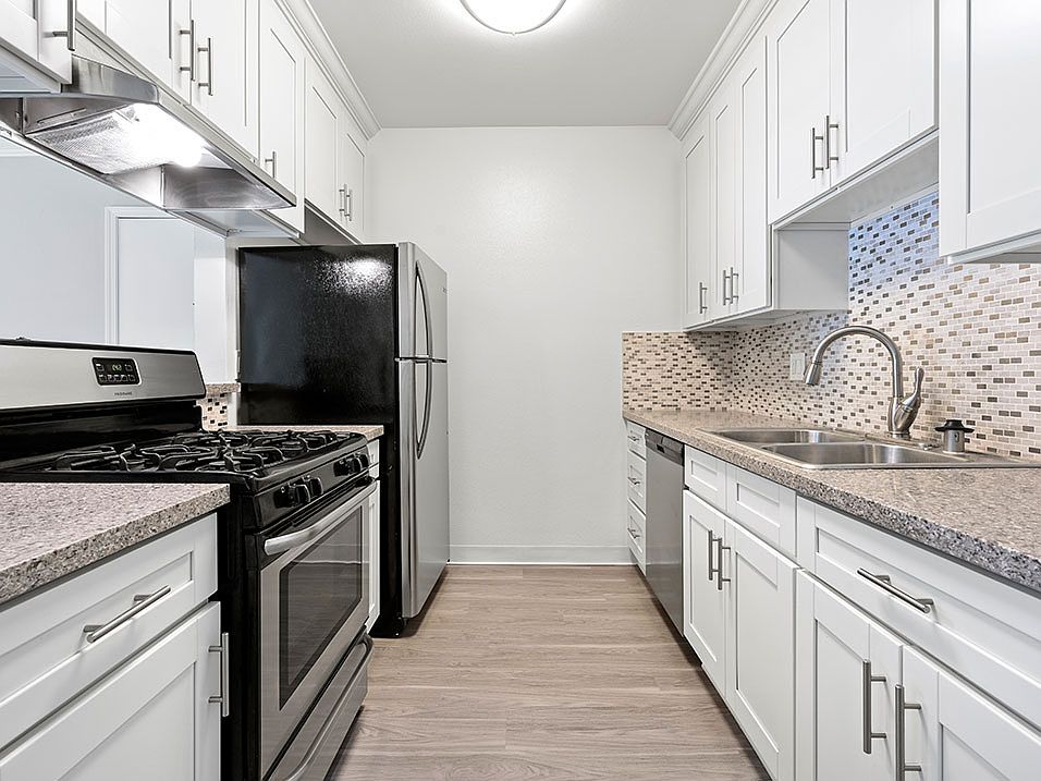 Custom tiled kitchen with stainless steel fridge, sink, and oven.