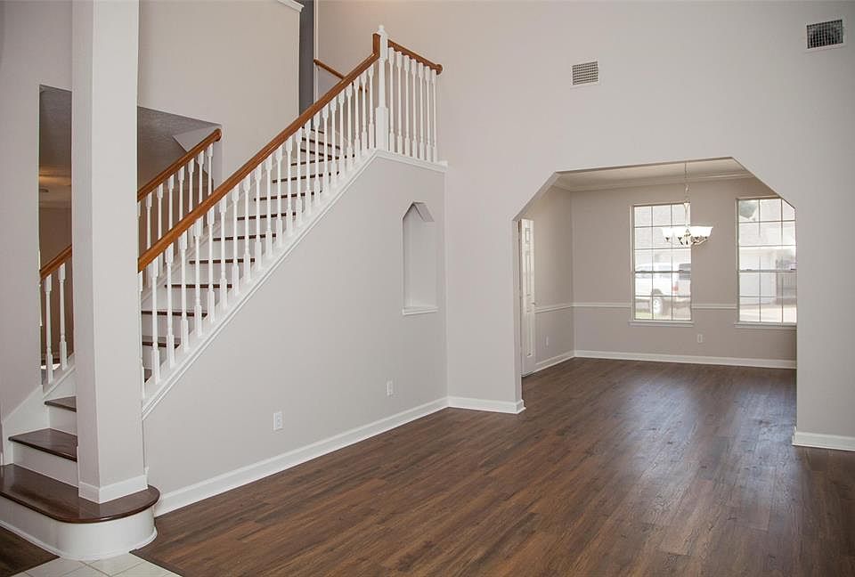 Grand entrance showcasing refurbished staircase. Formal sitting room with built in niche and formal dinning room are to the right.