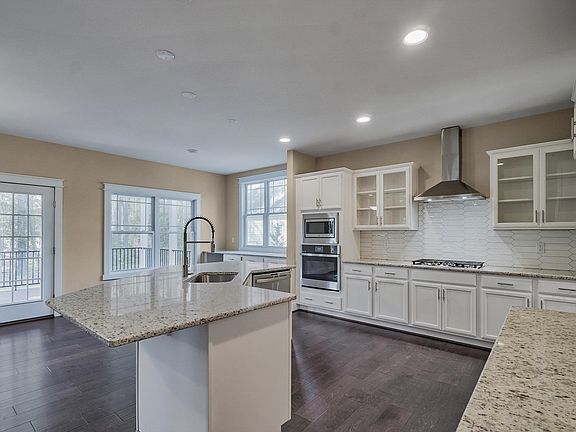 Modern kitchen in Poplar Village with white cabinets, granite countertops, and stainless steel appli