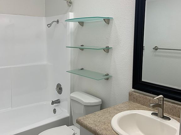 Bright airy bathroom has its own heater. Good sized cabinet for storage and additional decorative glass shelves provide a handy place for towels or accent pieces.