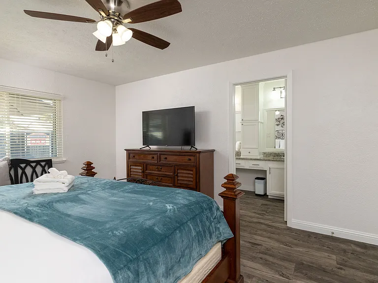 Relax in the primary bedroom featuring a luxurious king-size bed, full-body mirror, flat-screen Roku TV and an attached bathroom for your convenience. Don't forget the luggage carrier and hangers in the large, walk-in closet!
