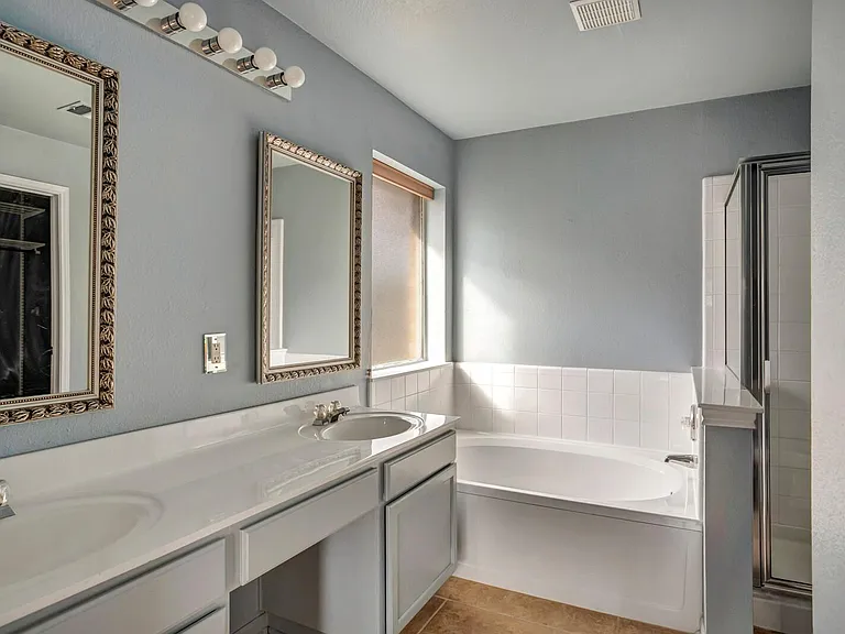 Master bathroom with double sink, large bath tub, and stand up shower.