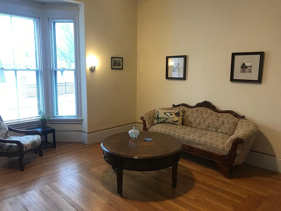 Large living room with period furniture. The bay window looks out onto a park. The living room gets plenty of natural light.