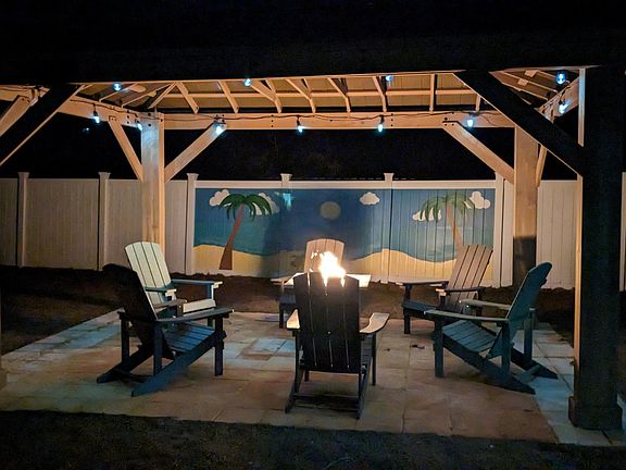 Relax in our spacious backyard with a cozy gazebo for morning coffee or evening chats. Enjoy the fire pit, roast marshmallows, or play cornhole. The hand-painted fence by a local artist with sea, sun, and palm tree designs adds a unique touch.