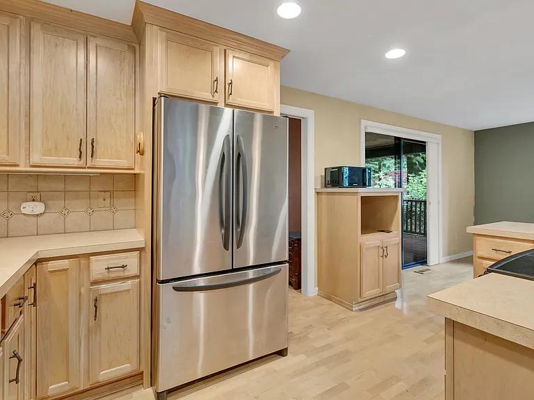 Large stainless-steel fridge, hardwood floors.