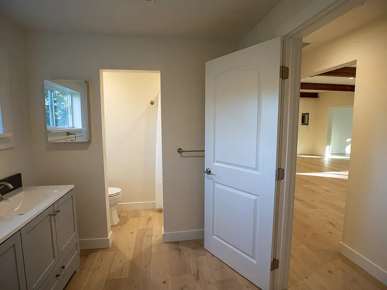 Bathroom with new vanity, fixtures and toilet/shower room. Two ways into the bathroom from the hallway and bedroom.