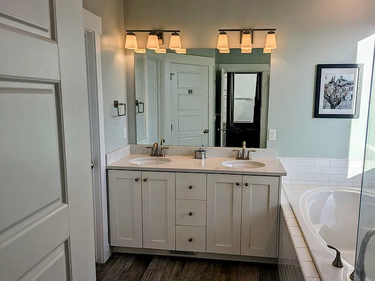 Master bathroom with double sink, large tub, glass enclosed shower, and large walk-in closet.