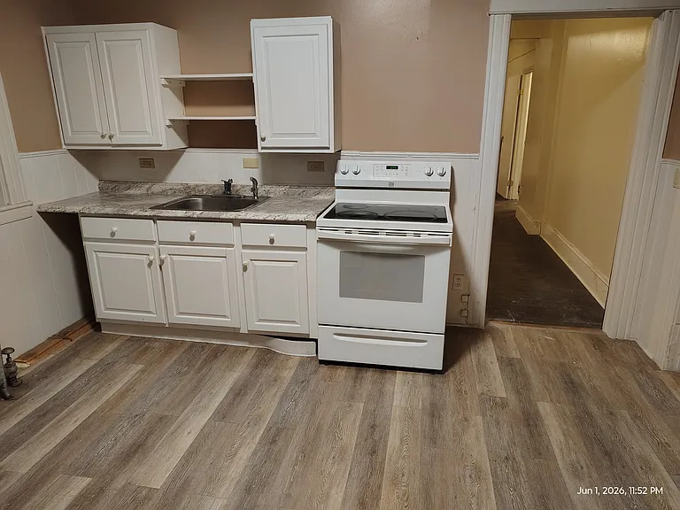 Kitchen sink, stove, cupboards. Looking North (toward the street) thru door into Dining room.