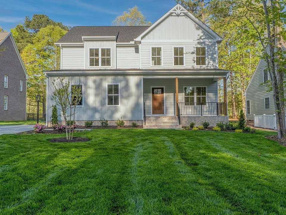 A sunny day highlights a two-story white house with a front porch, nestled among trees and lawns-a c