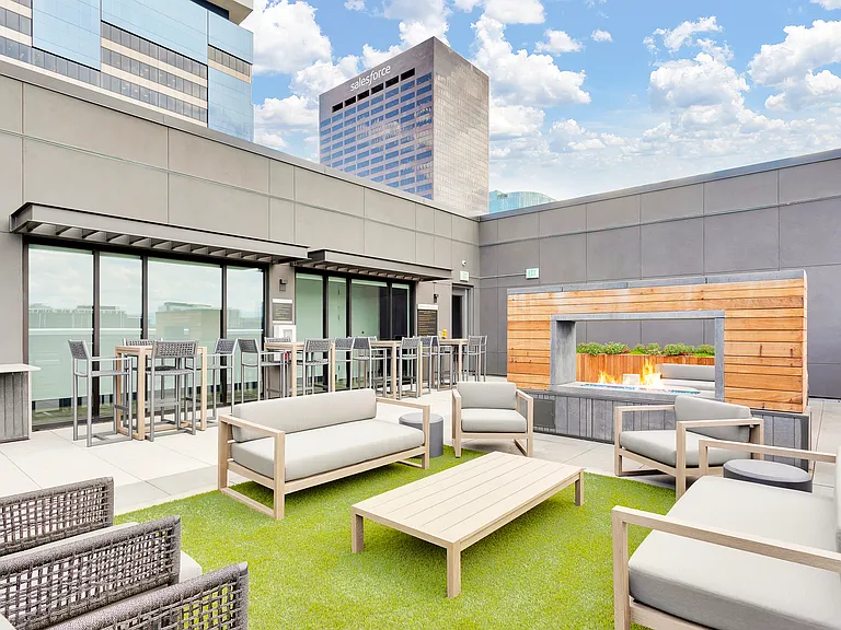 Modern rooftop patio with cozy fireplaceseating, stylish fire pit, and city skyline views, perfect for urban entertaining.