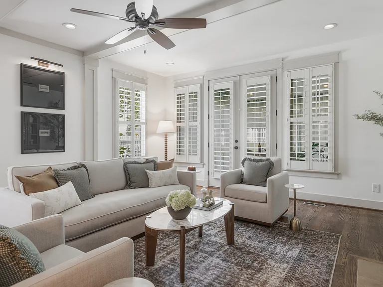Beautifully designed living room with a fireplace, ceiling fan and plenty of comfy seating. Smart TV, wood floors, and easy flow into the kitchen.
