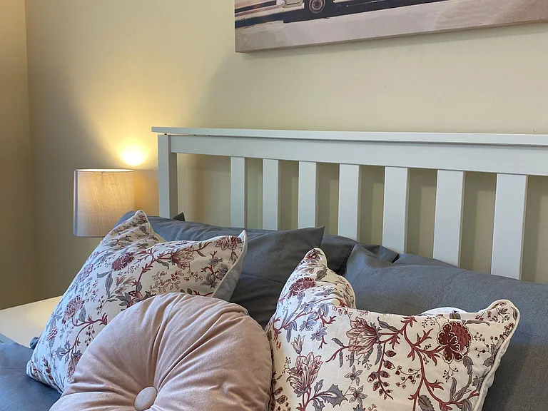 Furnished bedroom with a full-size bed, bedside lighting, and neutral walls accented by oversized art for a relaxing setup.