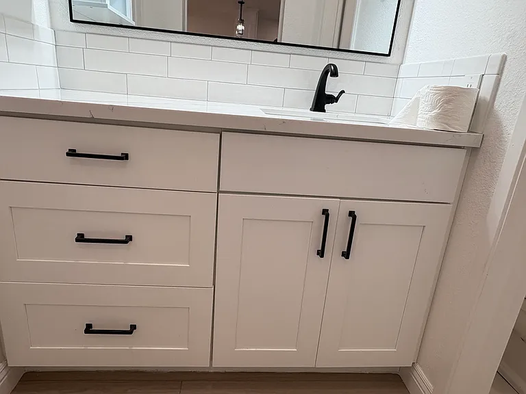Modern, stylish vanity with a tile backsplash with a dark contrast.