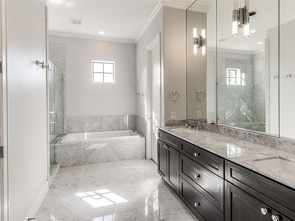 Elegantly appointed Primary Bath features marble floors, countertops, tub and shower surrounds. Large walk-in shower has frameless glass enclosure and