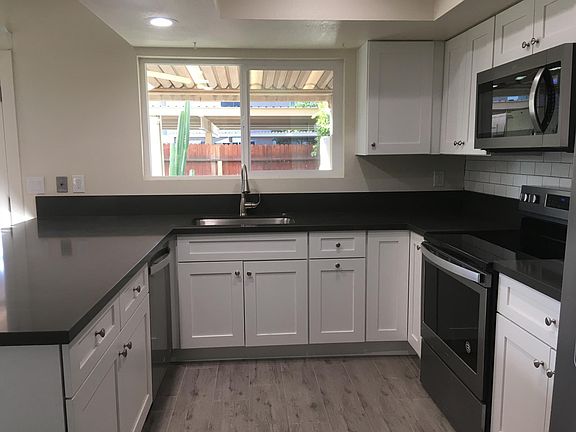 White kitchen, quartz counters, stainless appliances, tile floors