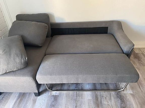 Spacious gray sectional sofa with soft cushions for a comfortable stay.