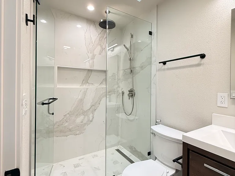 Hallway full bathroom with skylight and shower finished in frameless enclosure plus custom niche.