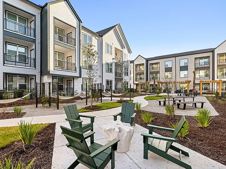 Beautifully landscaped apartment courtyard with hammock lounges, picnic areas, Adirondack seating, and outdoor social spaces.