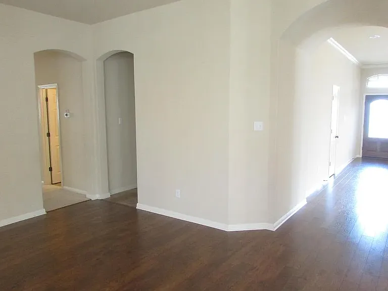 living room view to the entry door, guest bathroom + utility room and on the far left are two bedrooms separated by a flex space with storage room, one bathroom