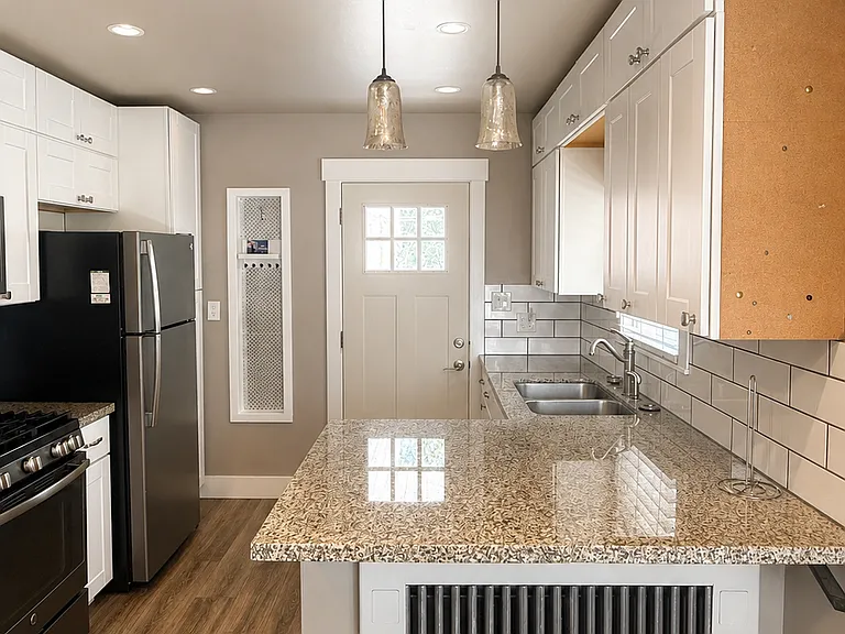 Renovated kitchen featuring granite countertops, subway tile backsplash, and ample cabinet space.