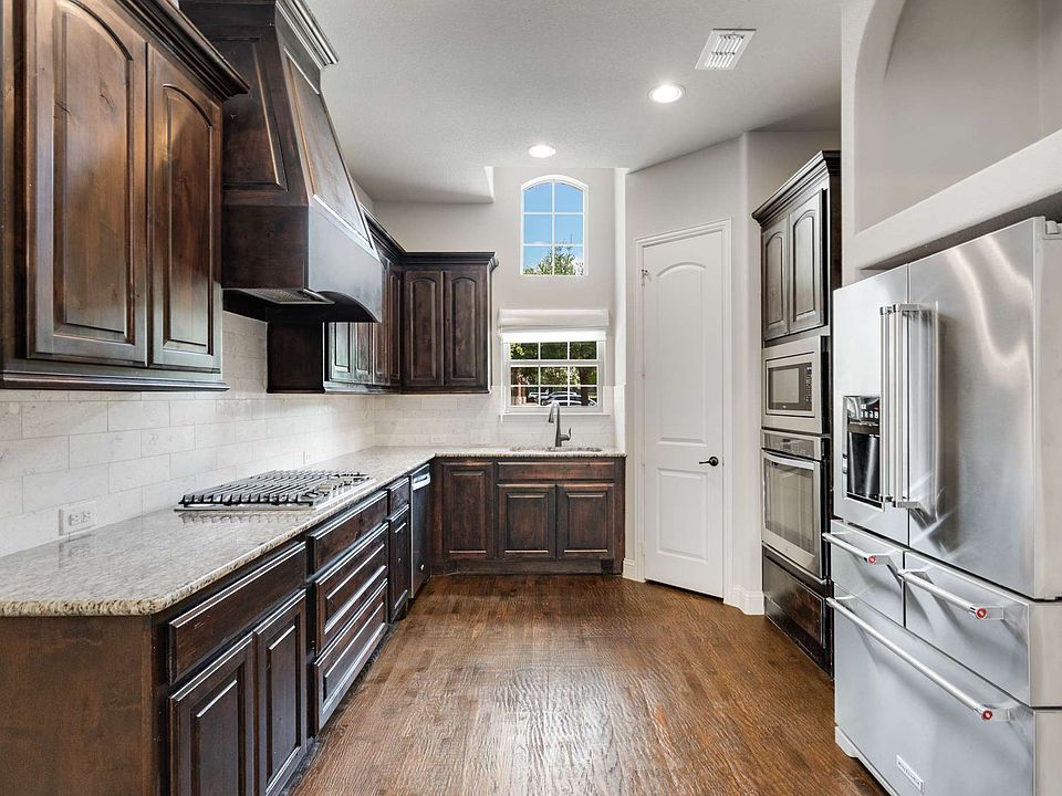 Kitchen featuring appliances with stainless steel finishes, dark brown cabinets, dark wood finished floors, custom exhaust hood, and recessed lighting