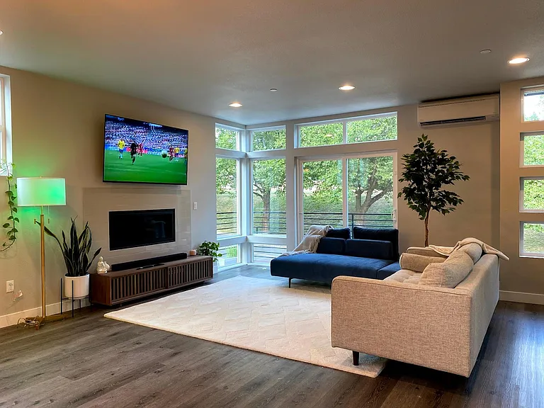 Living room with gas fireplace and huge windows and open floor plan.