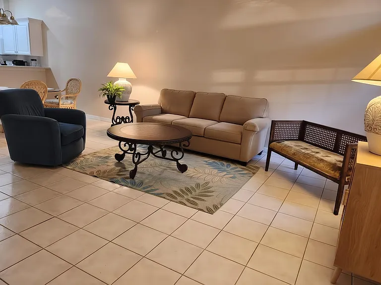 Open living area with tiled floors and comfortable seating, flowing into the adjacent dining nook and kitchen pass-through.