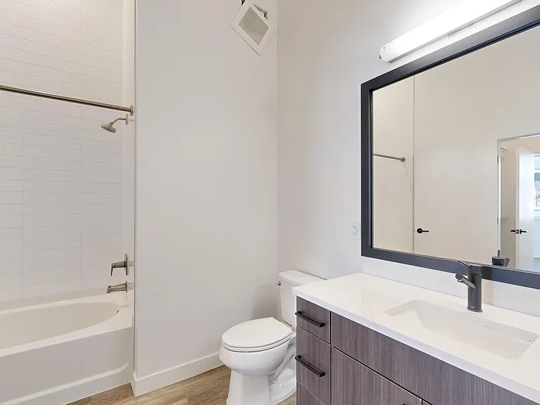 Apartment bathroom with large soaking tub and wood-style flooring.